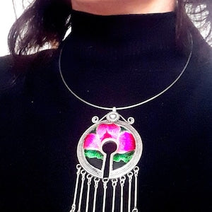 Silver pendant necklace with round medallion, pink and green accents, and dangling fringe