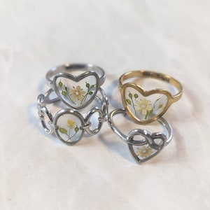 Pressed flower ring set with heart-shaped settings in silver and gold tones, openwork metal bands
