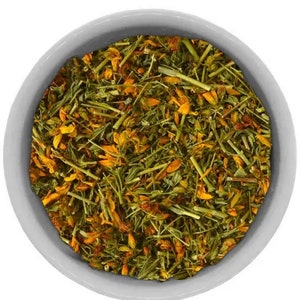 Dried arnica flower herb, loose yellow blossoms and green stems in a bowl