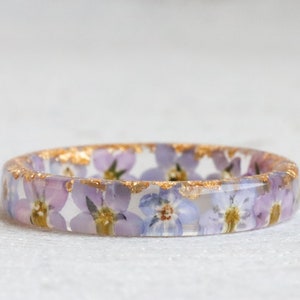 Clear resin ring band with pressed pink and blue forget-me-not flowers and gold flecks