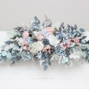 Dusty blue and blush pink floral arch arrangement with white blooms and greenery
