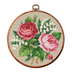 Round cross-stitch embroidery hoop with pink roses, green leaves, and white blossoms