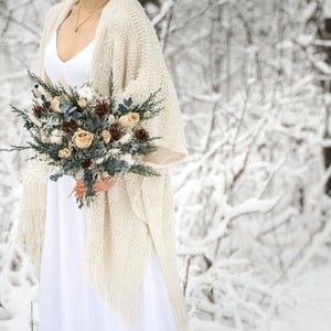 Bridal dried flower bouquet with white and beige blooms and evergreen greenery