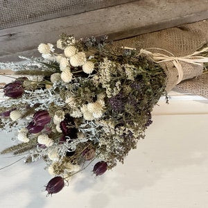 Dried flower bouquet with beige white and dark purple blooms, wrapped in burlap