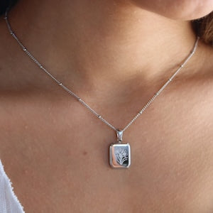 Silver square pendant necklace with small engraved design on a thin chain