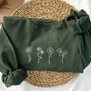 Dark green sweatshirt with white embroidered birth flowers and small bow on neckline