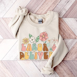 Beige crewneck sweatshirt with colorful floral Labor & Deliver front graphic