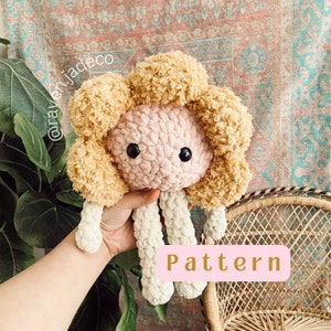 Crocheted plush lamb with curly beige wool, pink face, held in a hand