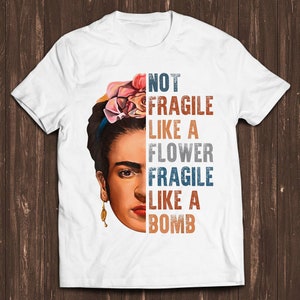 White graphic tee with portrait and text: "NOT FRAGILE LIKE A FLOWER"