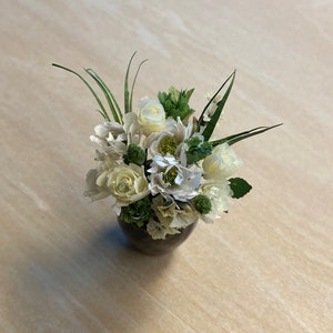Miniature flower bouquet with cream and white blooms in small vase