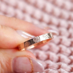 Gold floral band ring with small flower engraving across the top