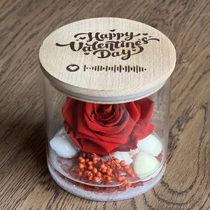 Red preserved rose in clear glass jar with round “Happy Valentine’s Day” lid