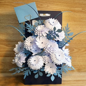 Blue flower display box with white daisies, foliage, and twine string tied on top