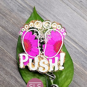 Floral badge reel with green leaf and pink heart 'PUSH' graphic, metal clip