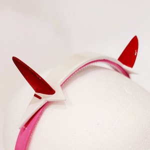 White and pink headband with red pointed horn headpiece accents