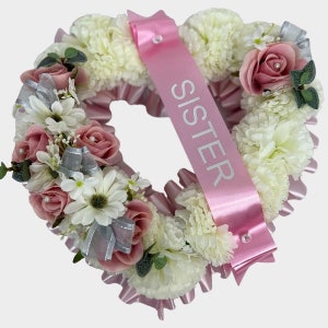 Artificial heart-shaped funeral wreath with pink and white flowers, satin ribbon 'SISTER'.