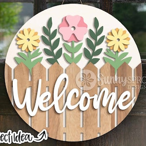 Round welcome door hanger sign with picket fence and floral accents, wooden cutout