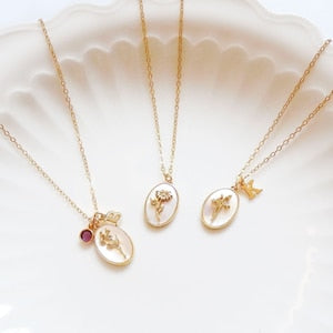 Gold-tone birth flower necklace with round locket pendants and small star charm