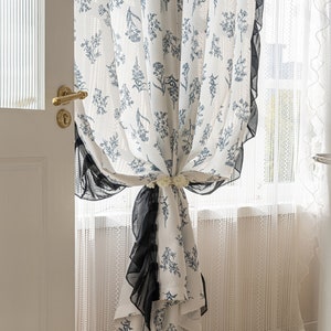 Floral white sheer curtain panel with blue leaf pattern and tied-back detail