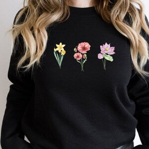 Black flower sweatshirt with three pink blossoms and green stems on the chest