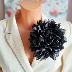 Black oversized organza flower brooch with layered petals on clothing lapel