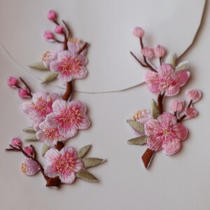Pink embroidered cherry blossom iron-on patch with small green leaf details
