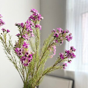Artificial wax flower stem with small purple blooms and green foliage