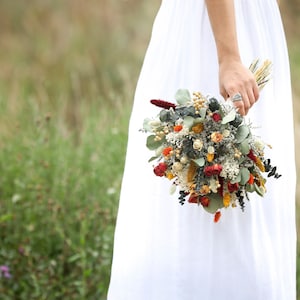 Autumn dried flower bridal bouquet with orange, red, and cream blooms and greenery