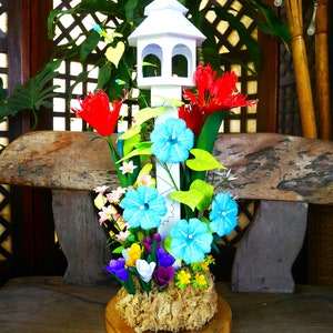 Spring Easter floral centerpiece with blue and red flowers and small white birdhouse