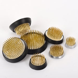Gold metal flower frog set with brass-toned spike pins on black bases