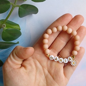 Children's beaded bracelet with name "HANNAH" and flower charm, pink beads