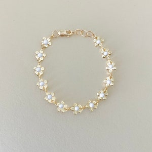 Gold-tone chain bracelet with small white flower charms and a secure clasp