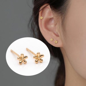 Gold flower stud earrings with small dangling star charms, gold-plated brass