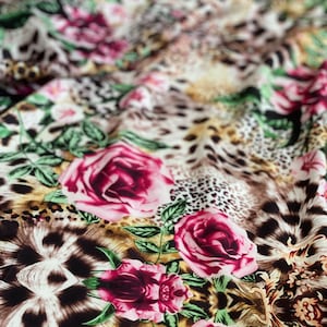 Silky satin fabric with leopard spots, red roses, and green leaves pattern