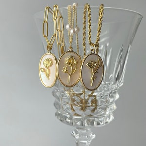 Gold-tone oval mother-of-pearl pendant necklaces with floral motif charms