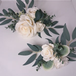 Wedding cake topper with white roses, eucalyptus leaves, and green floral accents