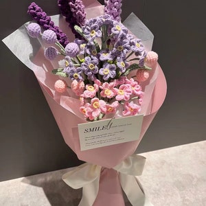 Handmade crochet flower bouquet with purple, pink and cream blooms, wrapped in pastel paper