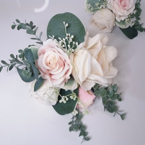 Heart-shaped cake topper with pink roses, cream flowers, and eucalyptus-style greenery