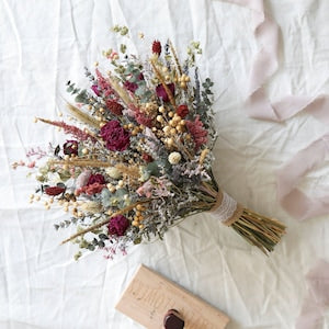 Dried bridal bouquet with dark teal and burgundy dried flowers, tied with twine