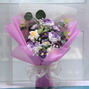 Handmade crochet flower bouquet wrapped in pink paper, with purple and white blossoms