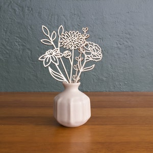 Wood flower bouquet in white ceramic vase with delicate white floral cutouts