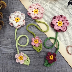 Crochet flower bookmarks with pink blossoms, yellow centers, and green stems and leaves
