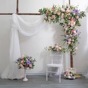 Floral wedding arch with pink, purple, and ivory blooms and green foliage