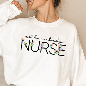 White mother-baby nurse sweatshirt with floral “nurse” graphic and script text