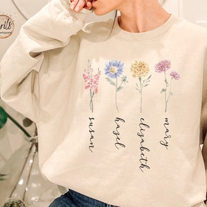 Cream sweatshirt with colorful flower graphic and cursive text on the front