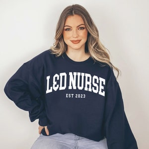 Navy crewneck sweatshirt with 'L&D Nurse' and 'EST 2023' printed text