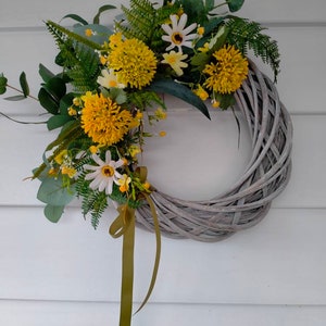 Handmade wreath with yellow faux flowers, green leaves, and a hanging yellow ribbon.