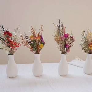 Set of mini dried flower bouquets in small cream bottle vases with green stems