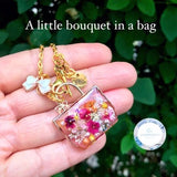 Gold-tone resin floral bag charm with square pendant, dried flowers, and heart bird charm