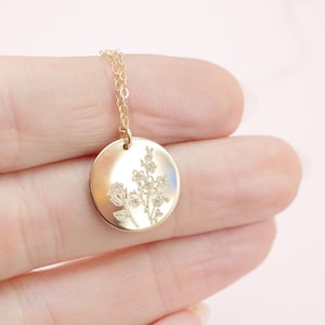 Gold-tone round locket necklace with engraved floral tree design and chain